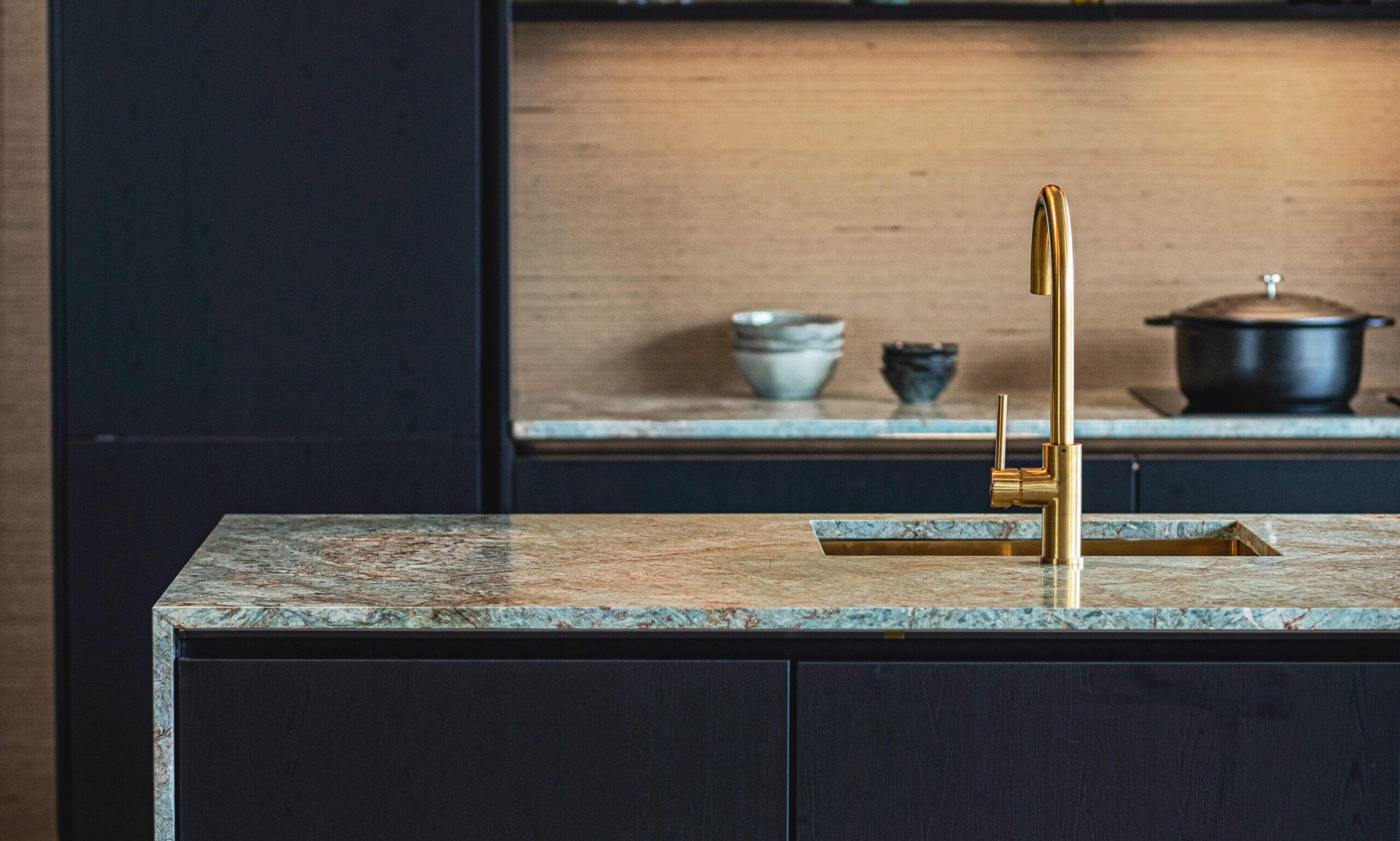 Luxe keukenblok met gouden kraan, geaccentueerd door hoogwaardige afwerkingen, geschikt voor moderne zorginstellingen.